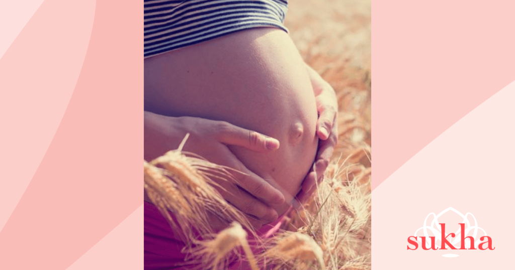 A woman holding her pregnant tummy with her hands for fertility yoga and support