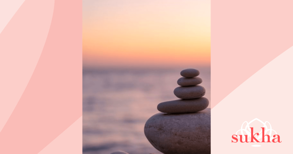 Anxiety and support sunset with glowing orange and yellow sky with rocks on top of each other stacked